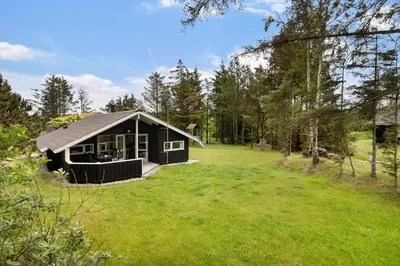 a black cabin in the middle of a grass field at LK599-Lokken-Stellavej-16 in Løkken
