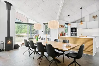 a dining room with a table and chairs and a fireplace at BL1535-Blokhus-Saetergaardsstien-5-A in Blokhus