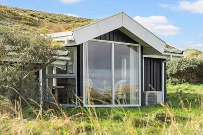 a small house with glass doors in a field at LK1947-Lokken-Madsinesvej-11 in Løkken
