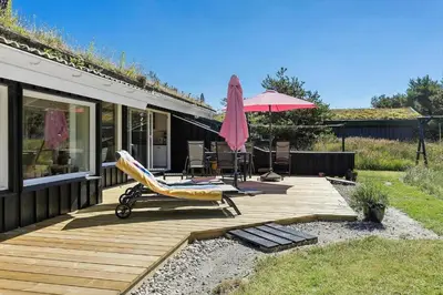 a wooden deck with a chair and an umbrella at BL102-Saltum-Kvansletten-13 in Saltum