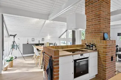a kitchen with white cabinets and a brick wall at BL1402-Blokhus-Bag-Hojen-57 in Blokhus