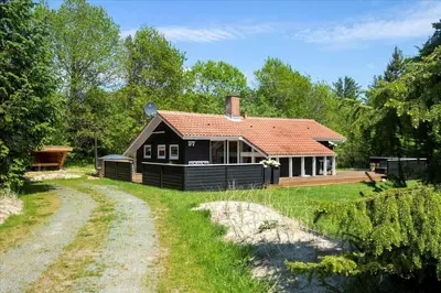 a black house with a red roof and a dirt road at BL1402-Blokhus-Bag-Hojen-57 in Blokhus