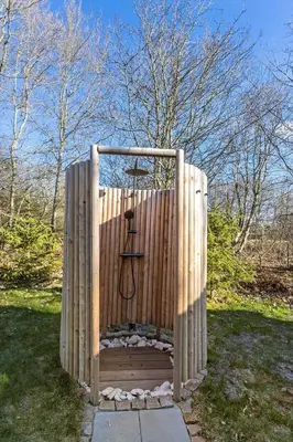 a wooden fence with a stand in the grass at BL1402-Blokhus-Bag-Hojen-57 in Blokhus