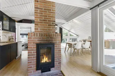 a brick fireplace in a living room with a table at BL1402-Blokhus-Bag-Hojen-57 in Blokhus