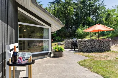a table with an umbrella next to a building at BL368-Blokhus-Bag-Hojen-19 in Blokhus