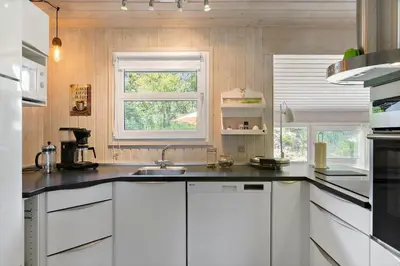 a kitchen with white cabinets and a sink and a window at BL368-Blokhus-Bag-Hojen-19 in Blokhus