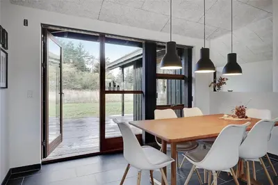 a dining room with a wooden table and white chairs at BL1611-Saltum-Trehoje-3 in Saltum