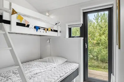 a small bedroom with a bunk bed and a window at BL1635-Blokhus-Lyngdraget-19 in Blokhus