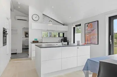 a kitchen with white cabinets and a clock on the wall at BL1635-Blokhus-Lyngdraget-19 in Blokhus