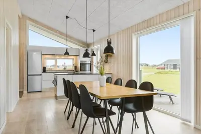 a kitchen and dining room with a wooden table and chairs at LK2031-Lokken-Kringelbaekvej-55 in Løkken