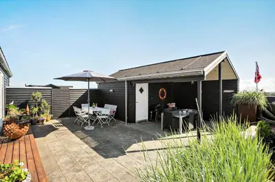 a patio with a table and an umbrella at LK553-Lokken-Rosavej-7 in Løkken
