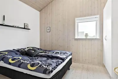 a bedroom with a bed in a room with a window at BL1629-Blokhus-Klitgaardsvej-29 in Blokhus