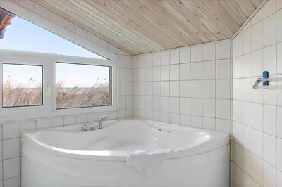 a white bath tub in a bathroom with a window at LK2130-Lokken-Lottesvej-23 in Løkken