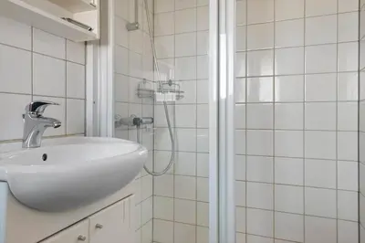 a white bathroom with a sink and a shower at LK2130-Lokken-Lottesvej-23 in Løkken