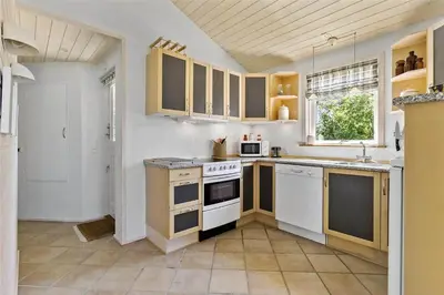 a kitchen with wooden cabinets and white appliances at BL547-Blokhus-Skraavejen-8 in Blokhus
