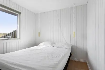a bedroom with a bed with white sheets and a window at LK2117-Lokken-Kettrup-Bjerge-Vej-55 in Løkken