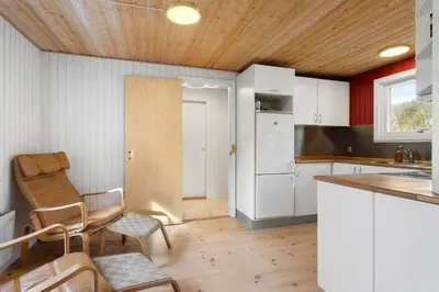 a kitchen with white cabinets and a table and a chair at LK2117-Lokken-Kettrup-Bjerge-Vej-55 in Løkken
