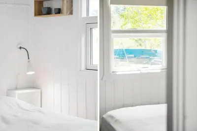 a white bedroom with a window and a bed at BL1598-Blokhus-Raevestien-2 in Blokhus