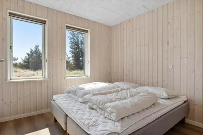 a bed in a room with two windows at LK2116-Lokken-Marthasvej-5-C in Løkken
