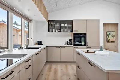 a kitchen with white cabinets and a large window at LK2116-Lokken-Marthasvej-5-C in Løkken