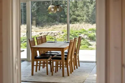 a dining room table and chairs with a large window at LK2116-Lokken-Marthasvej-5-C in Løkken