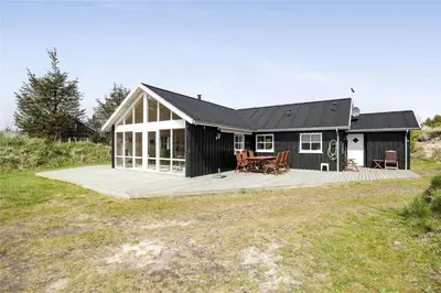 a large black house with a wooden deck at BL704-Blokhus-Soren-Petersvej-7 in Blokhus