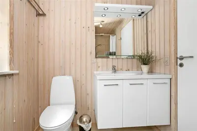 a bathroom with a toilet and a sink and a mirror at BL704-Blokhus-Soren-Petersvej-7 in Blokhus