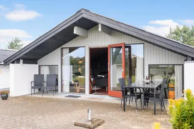 a house with a table and chairs on a patio at BL1309-Blokhus-Quintusvej-22 in Blokhus