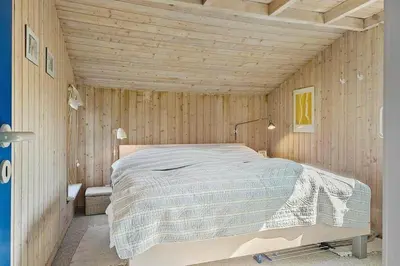 a bedroom with a bed in a wooden wall at BL1235-Blokhus-Malinsvej-9 in Blokhus