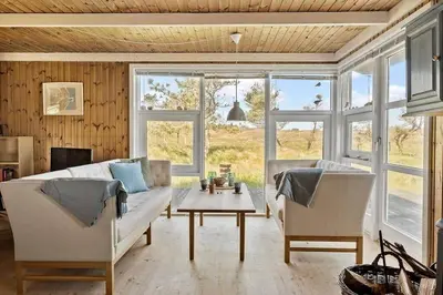 a living room with a couch and a table and windows at BL1235-Blokhus-Malinsvej-9 in Blokhus
