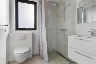 a white bathroom with a toilet and a shower at LK2144-Lokken-Kringelbaekvej-31 in Løkken