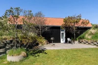 a black house with a red roof and a yard at BL1375-Blokhus-Klitvejen-15 in Blokhus