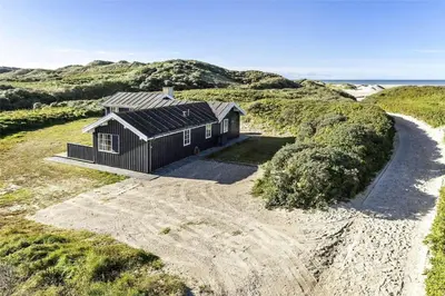 a black house on a beach with the ocean at BL1241-Saltum-Bondagervej-2 in Saltum