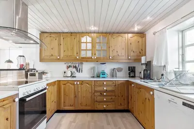 a kitchen with wooden cabinets and white appliances at BL1454-Pandrup-Rodhusvej-215 in Pandrup