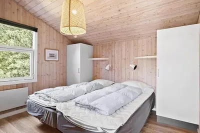 a bedroom with a large bed in a room with wooden walls at BL209-Saltum-Silkeborgvej-6 in Saltum