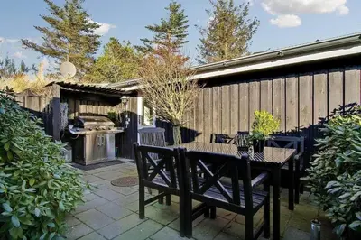 a patio with a table and chairs and a grill at BL1258-Blokhus-Frederiksensvej-19 in Blokhus