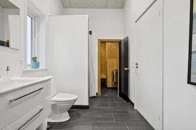 a white bathroom with a toilet and a sink at LK2167-Lokken-Kringelbaekvej-12 in Løkken