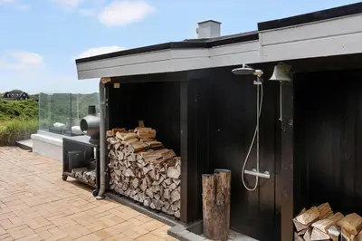 a black building with a pile of fire wood at LK2173-Lokken-Ruthsvej-9 in Løkken