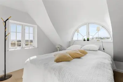 a white bedroom with a white bed with two windows at BL672-Pandrup-Strandfogdensvej-56 in Pandrup