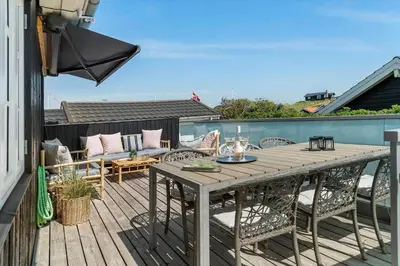a wooden deck with a table and chairs on a balcony at BL1637-Blokhus-Norresundbyvej-2 in Blokhus