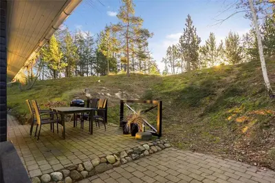 a patio with a table and chairs and a hill at BL946-Blokhus-Graevlingevej-8 in Blokhus