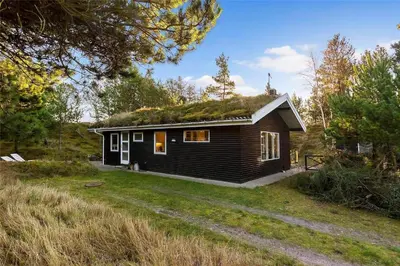 a small house with a grass roof on a field at BL946-Blokhus-Graevlingevej-8 in Blokhus