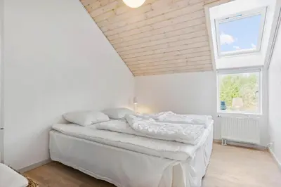 a bedroom with a bed with white sheets and a window at BL1619-Blokhus-Klitheden-Nord-42 in Blokhus