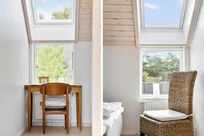 a room with a table and a chair and two windows at BL1619-Blokhus-Klitheden-Nord-42 in Blokhus