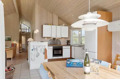 a kitchen with a table and a white refrigerator at BL1382-Blokhus-Gyvelvej-20-A in Blokhus