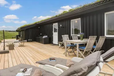 a deck with a table and chairs on a house at BL1020-Pandrup-Hunetorp-Klitvej-257 in Pandrup