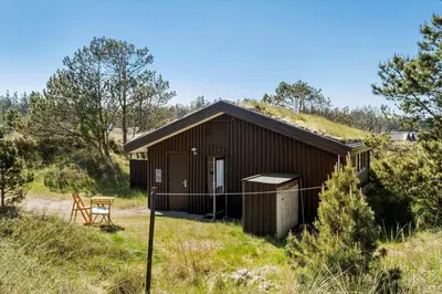 a small brown building in a field with a table at BL1225-Pandrup-Flaskehalsen-1 in Pandrup