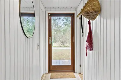 a hallway with a wooden door and a mirror at BL1735-Pandrup-Rodhus-Skolevej-56 in Pandrup