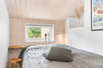 a bedroom with a bed and a window at BL1396-Blokhus-Laerkevej-8 in Blokhus