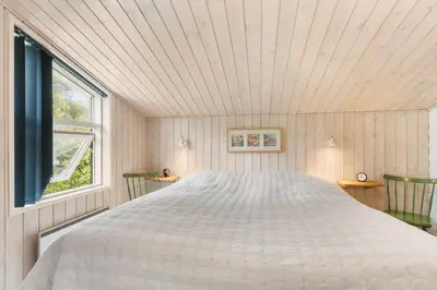 a large white bed in a room with a window at BL1396-Blokhus-Laerkevej-8 in Blokhus